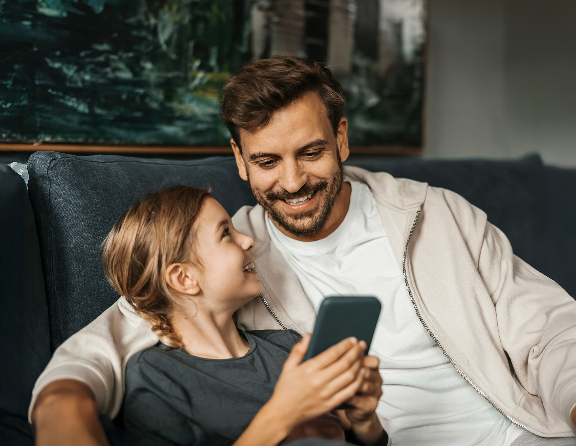 Pappa och barn håller i en mobiltelefon med Munipal avfallsappen i